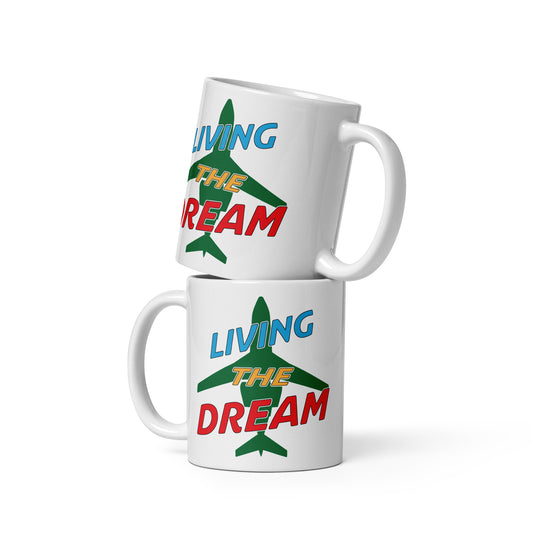 Ceramic white glossy mug with "Living The DreamCaution" over a green silhouette of a jet on the front and back.